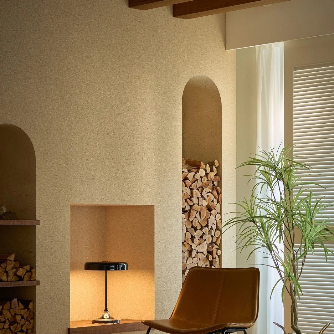 Black disc table lamp with rotating dimmer base, in a warm corner with an armchair