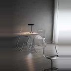 Black disc table lamp with rotating dimmer base, on a table in a grey room