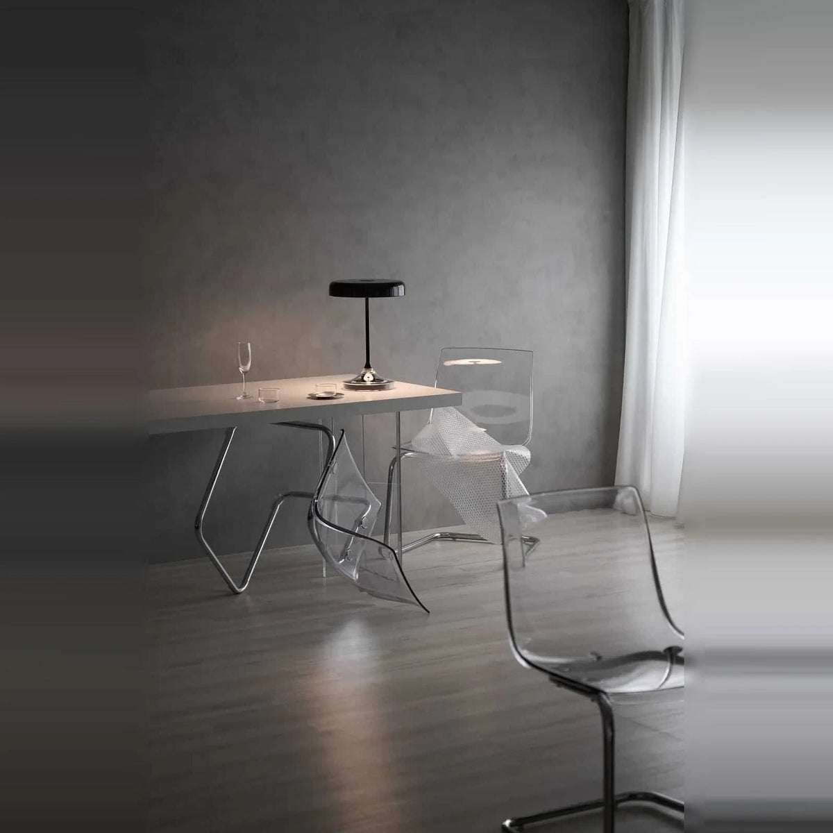Black disc table lamp with rotating dimmer base, on a table in a grey room