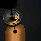 Black disc table lamp with rotating dimmer base, looking down at the gear mechanism