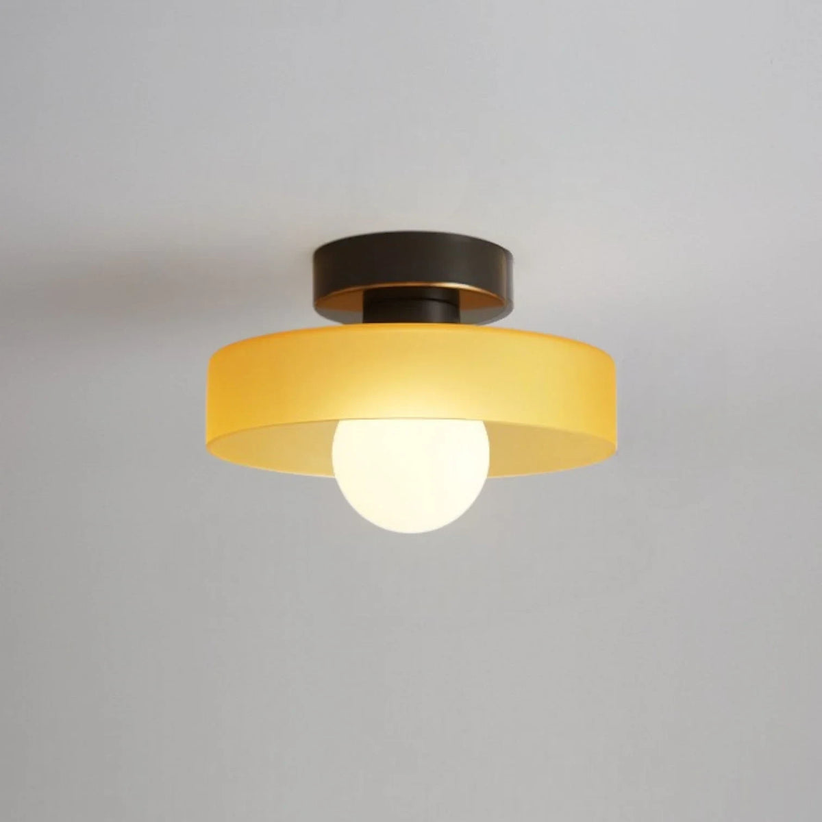 Round glass flush ceiling light, with a black base and orange glass