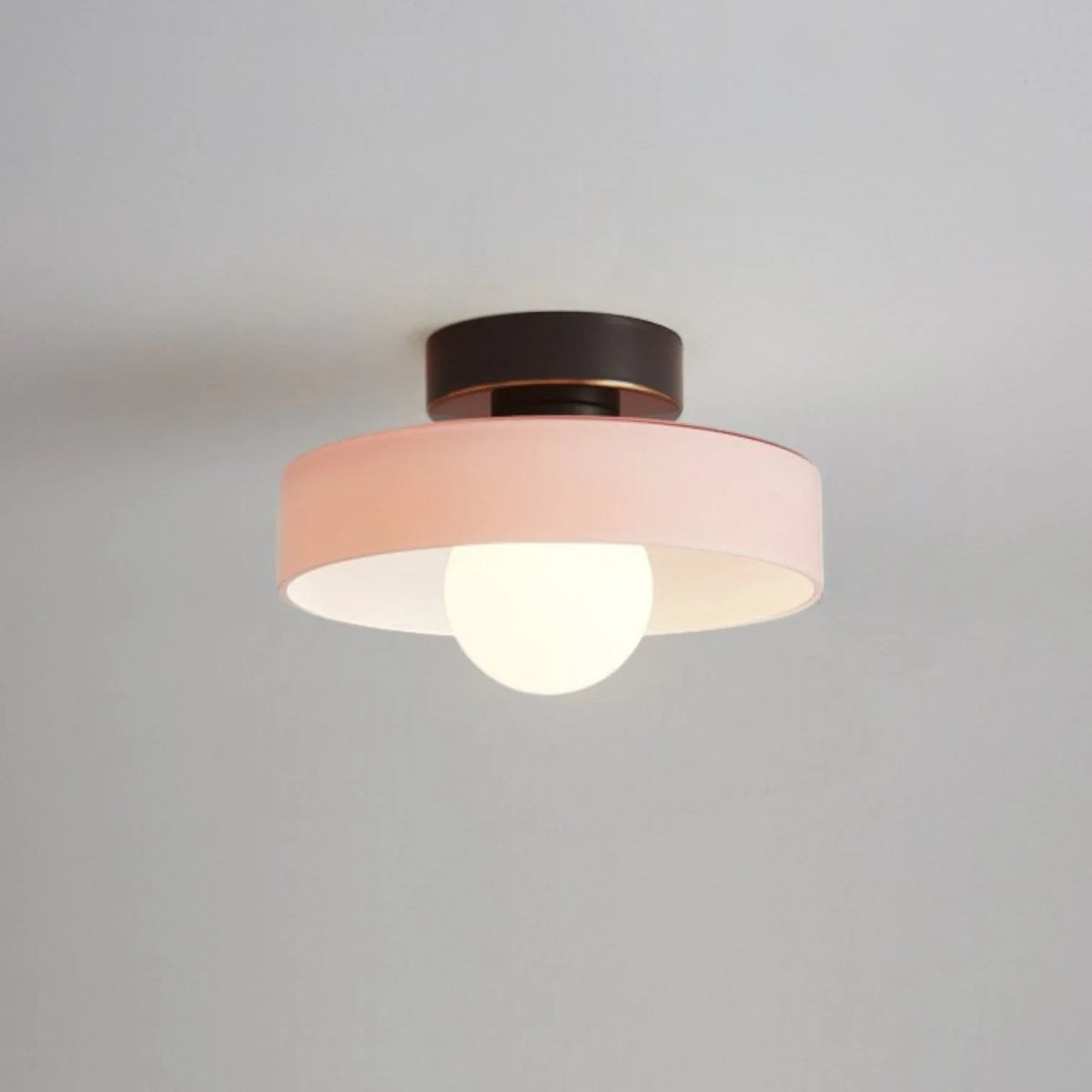 Round glass flush ceiling light, with a black base and pink glass