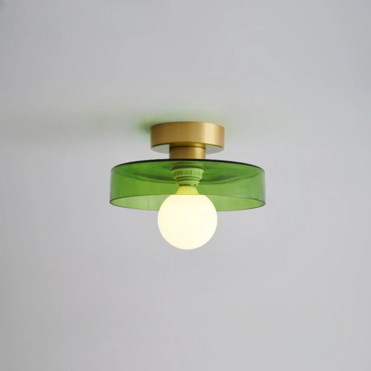 Round glass flush ceiling light, with a gold base and green glass