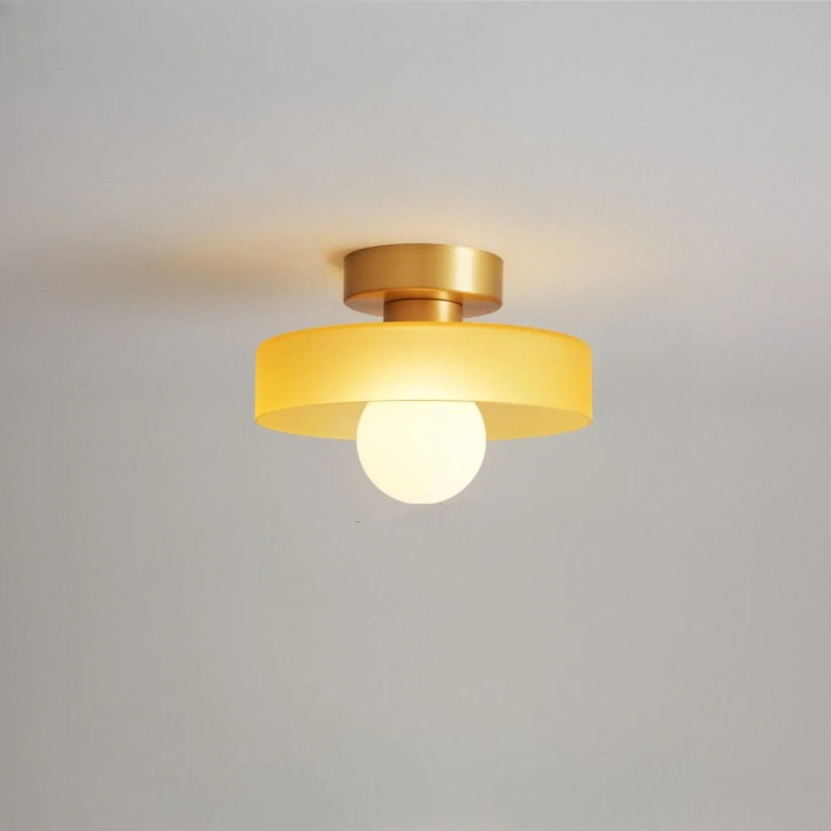 Round glass flush ceiling light, with a gold base and orange glass