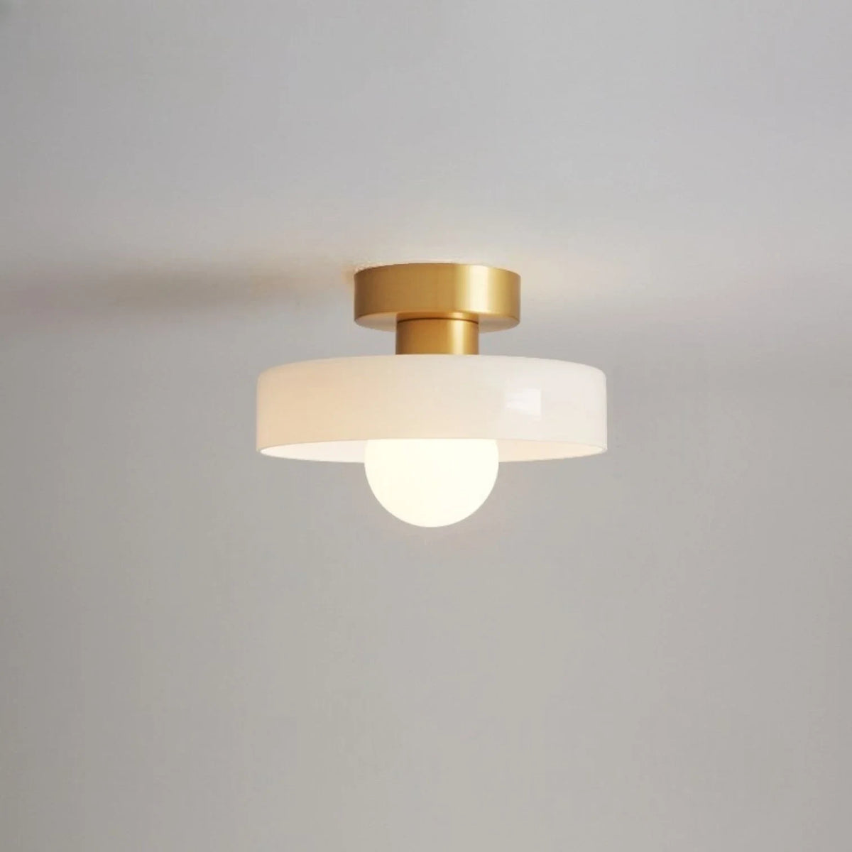 Round glass flush ceiling light, with a gold base and white glass
