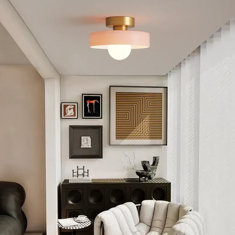 Round glass flush ceiling light, with a gold base and pink glass in a living room