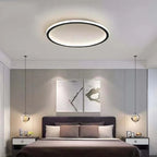 Round LED ring flush ceiling light, in black above a bed