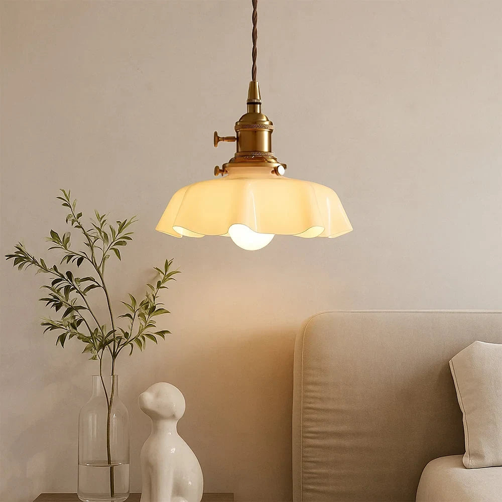 Scalloped cream glass pendant light with a brass fitting, above a sofa