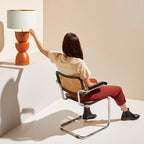 Sculpted stacked ceramic table lamp, on a shelf above a woman in a chair