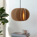 Sculptural white oak pendant, above a side table with a plant