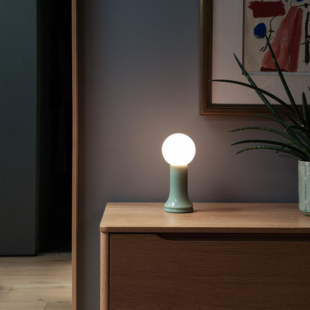 Mouth-blown glass table lamp in sea green, on a bedside cabinet