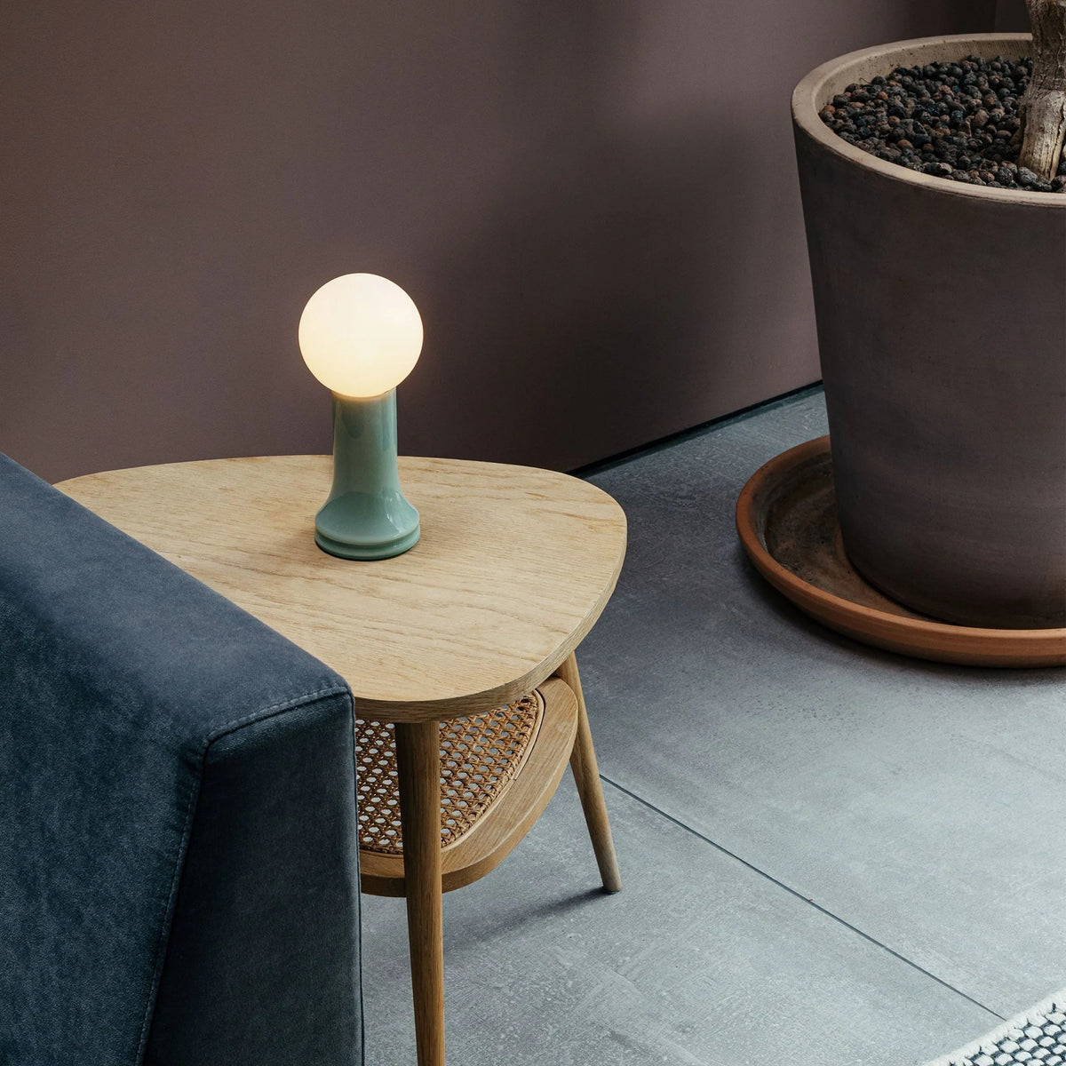 Mouth-blown glass table lamp in sea green, on a side table beside a sofa