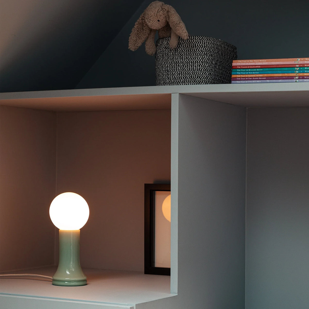 Mouth-blown glass table lamp in sea green, on a shelf in a room
