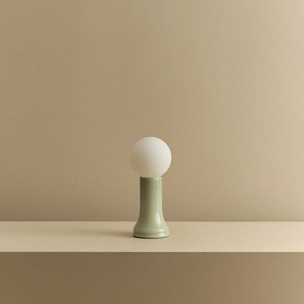 Mouth-blown glass table lamp in sea green, unlit, on a shelf