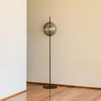 Single globe floor lamp in mouth-blown glass, in smoke grey beside a wall