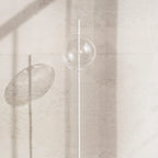 Single globe floor lamp in mouth-blown glass, in clear glass against a stone wall