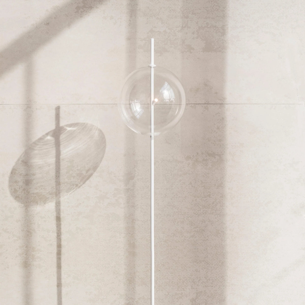 Single globe floor lamp in mouth-blown glass, in clear glass against a stone wall