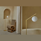 Slim articulated floor lamp with opal glass globe, matte brass, in a styled corner
