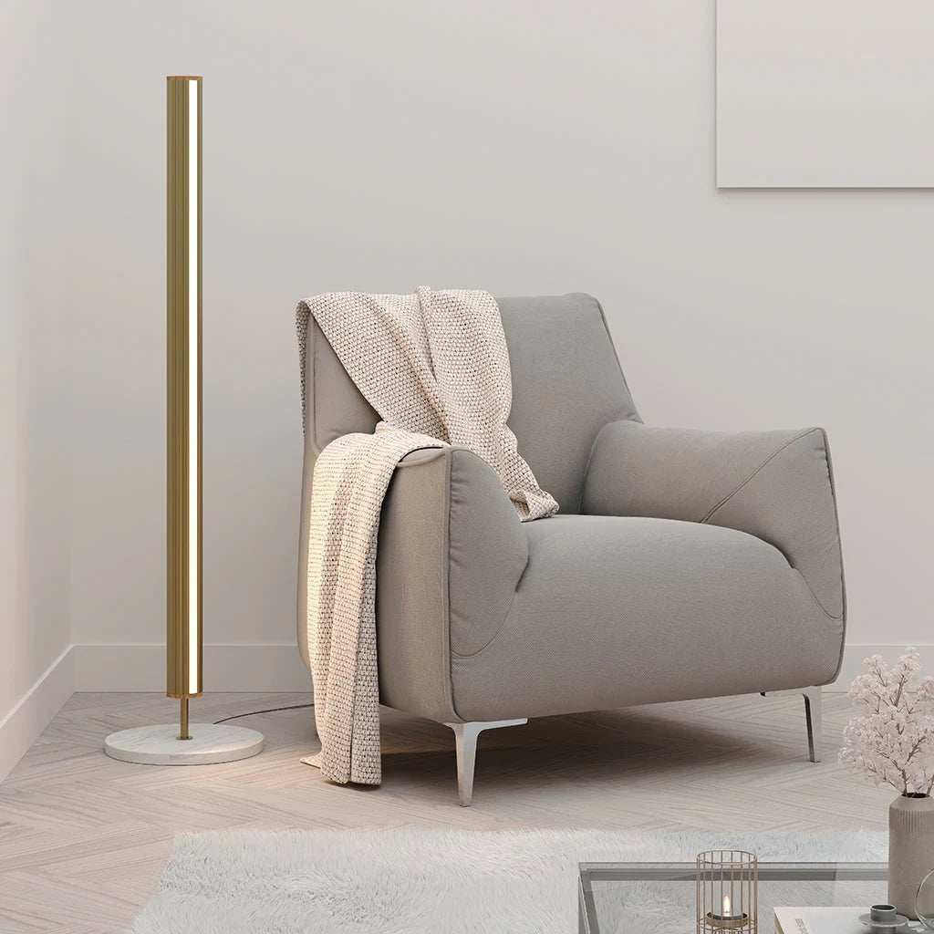 Slim LED column floor lamp with marble base, beside a grey armchair