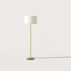 Slim column floor lamp with marble base, in matte brass, shown with a white drum shade (shade not included)