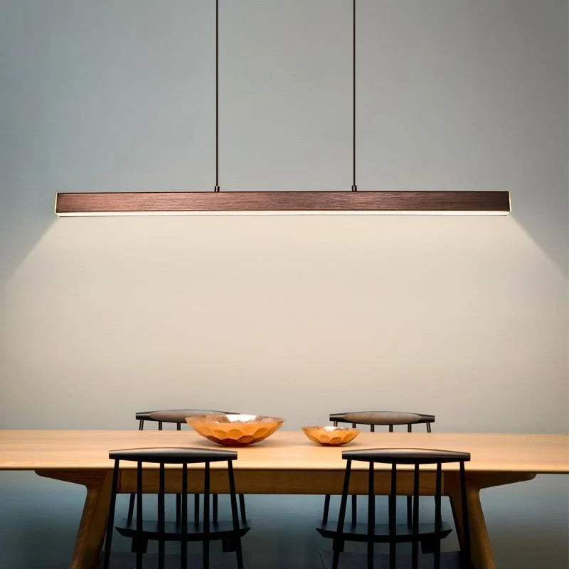 Slim linear LED pendant, in brown, over a wooden dining table