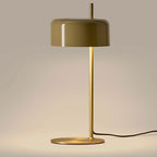 Slim stem table lamp with domed disc shade, in olive, with a brass frame, lit