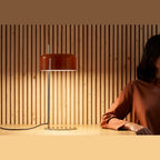 Slim stem table lamp with domed disc shade, in rust red, on a table