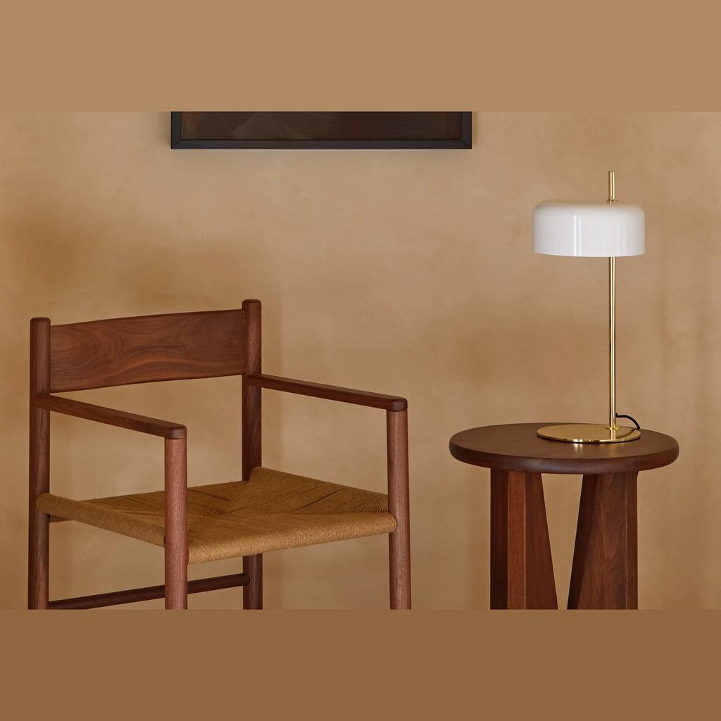 Slim stem table lamp with domed disc shade, in white, with a brass frame, on a side table