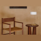 Slim stem table lamp with domed disc shade, in white, with a brass frame, on a side table