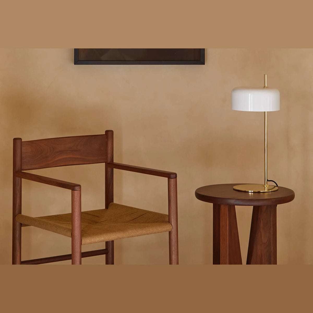 Slim stem table lamp with domed disc shade, in white, with a brass frame, on a side table
