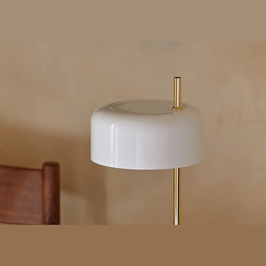 Slim stem table lamp with domed disc shade, close-up of a white shade on a brass stem