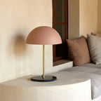 Slim stem table lamp base with black marble disc, with a brass stem and a pink dome shade (not included)