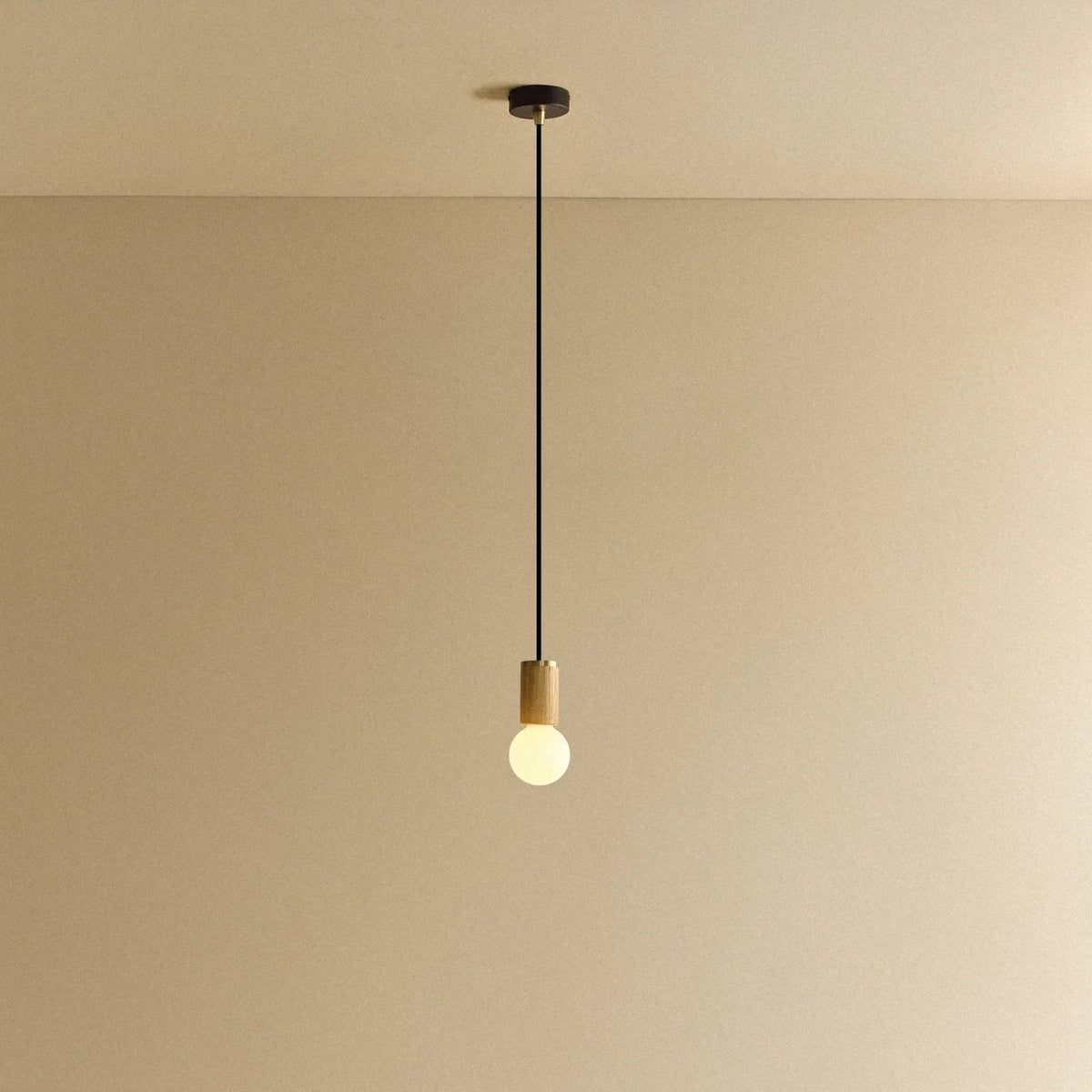 Small dim-to-warm globe pendant, oak, lit, against a plain wall
