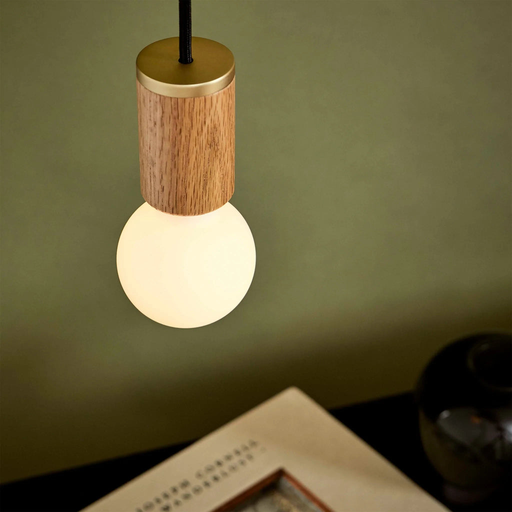 Small dim-to-warm globe pendant, oak, close-up of the lit globe and oak holder