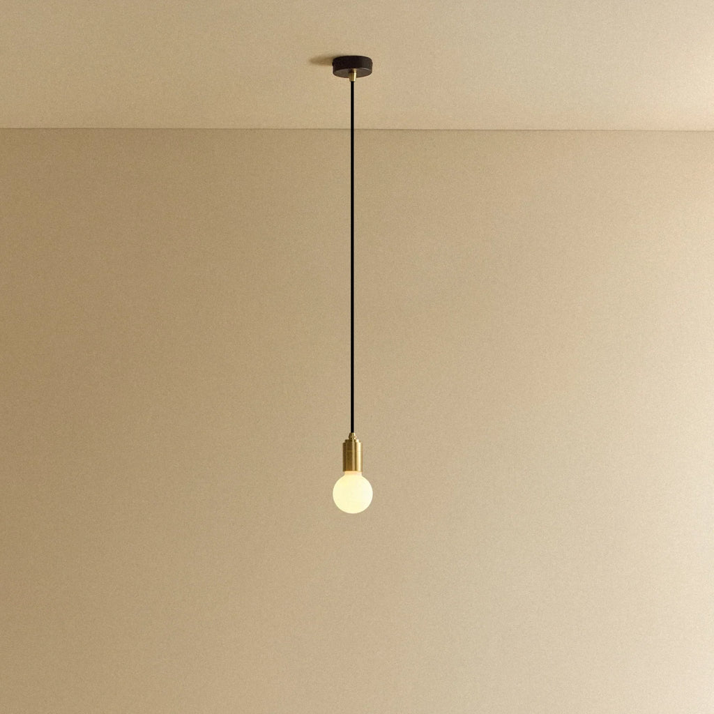 Small opal sphere pendant, in brass, lit, against a plain wall