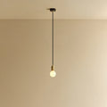 Small opal sphere pendant, in brass, lit, against a plain wall