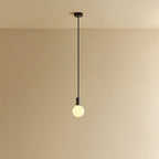 Small squat matte white glass pendant, graphite, lit, against a plain wall