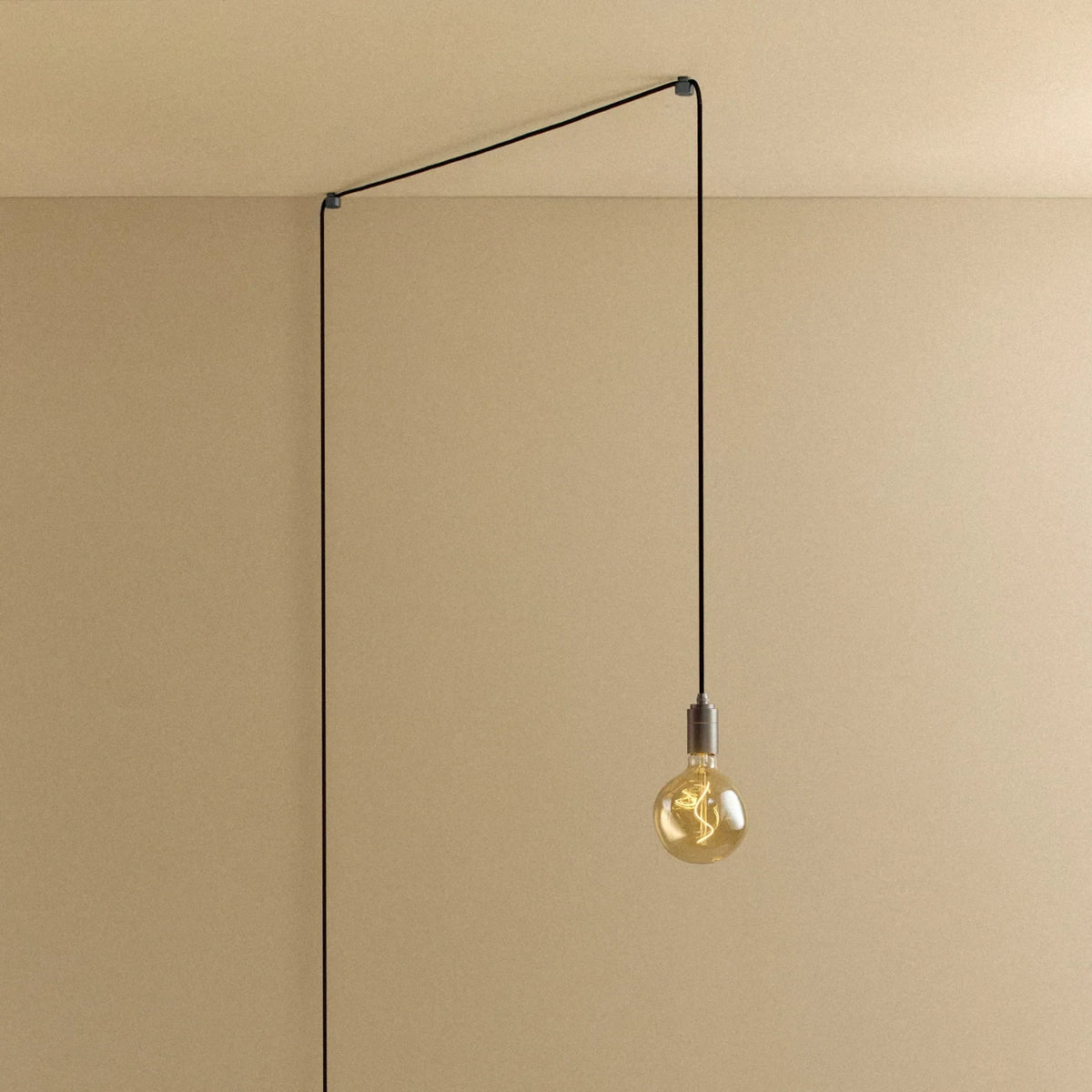 Plug-in pendant with small tinted bulb, graphite, lit, hung from a wall node