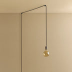 Plug-in pendant with small tinted bulb, graphite, lit, hung from a wall node, another angle