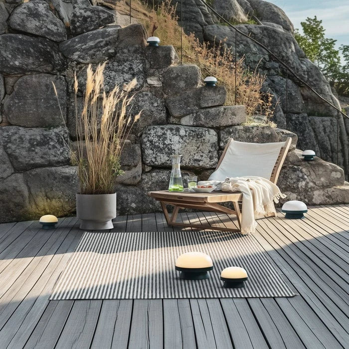 Cordless solar dome table lamp in forest green, on a rocky terrace at dusk