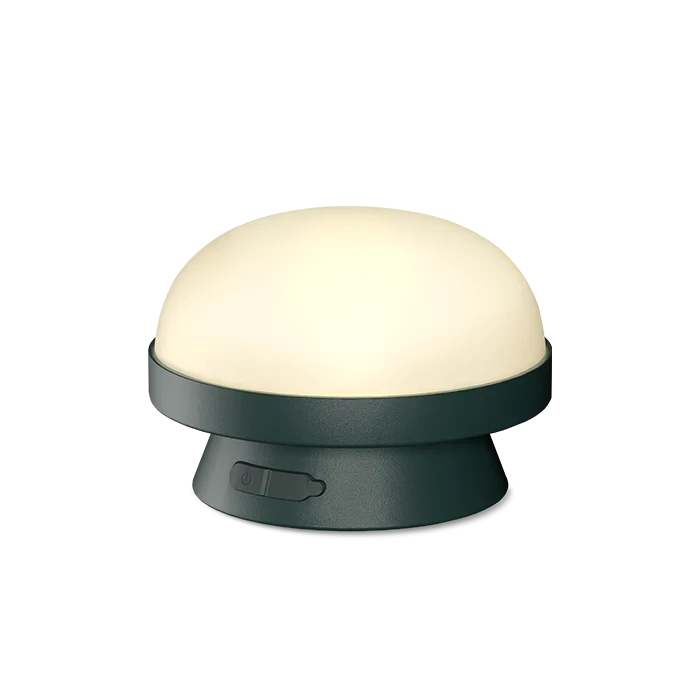 Cordless solar dome table lamp in forest green, lit on a white background