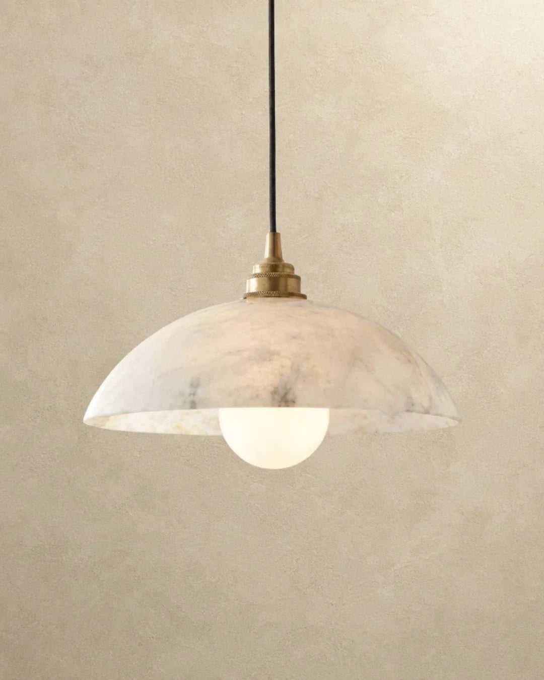 Solid marble dome pendant light, lit on a plain wall