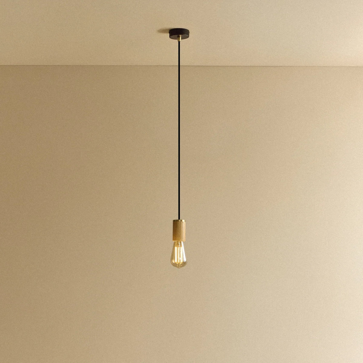 Squirrel Cage Filament Bulb Pendant, in oak, lit, against a plain wall