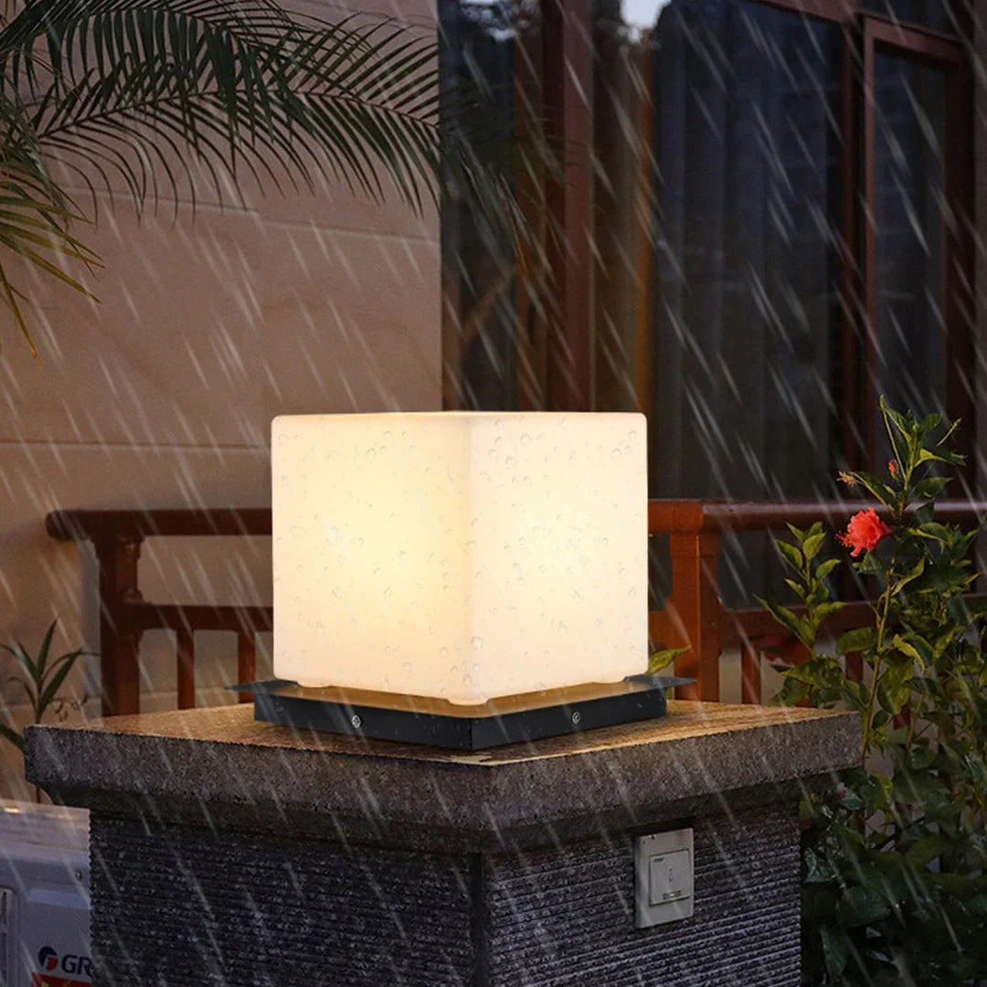 Outdoor pillar light, cube shade lit on a stone pillar