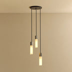 Three-drop cluster pendant in cast stainless steel with glass bulbs, lit, against a plain wall