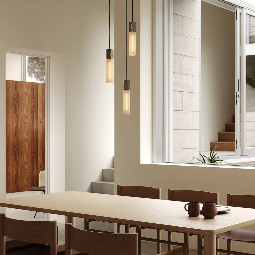 Three-drop cluster pendant in cast stainless steel with glass bulbs, over a dining table