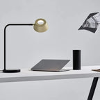 Slim desk table lamp with rotating shade, on a desk beside a laptop