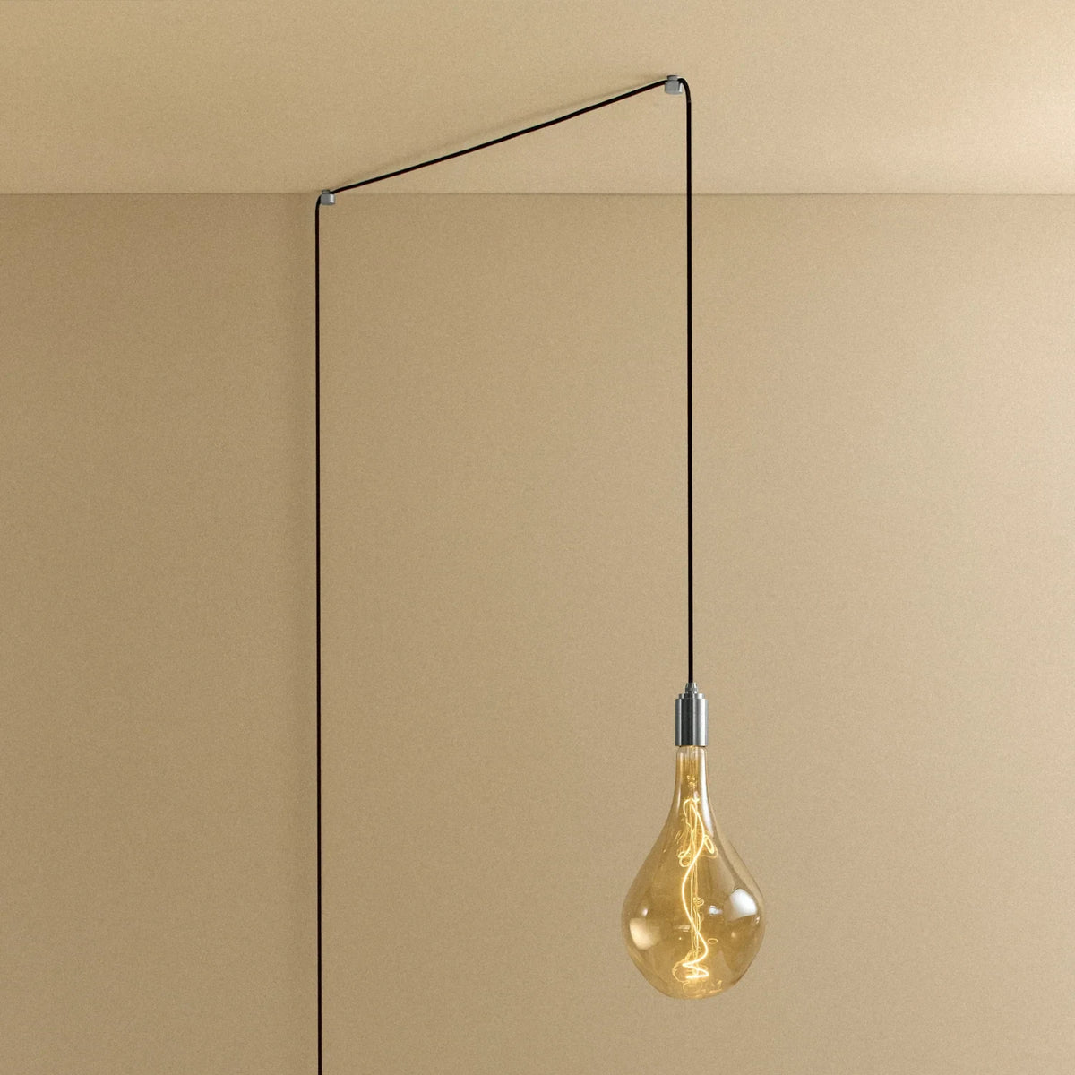 Tall tinted bulb plug-in pendant, routed across the ceiling and down the wall