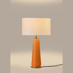 Tapered ceramic column table lamp, lit, with a linen shade (not included)