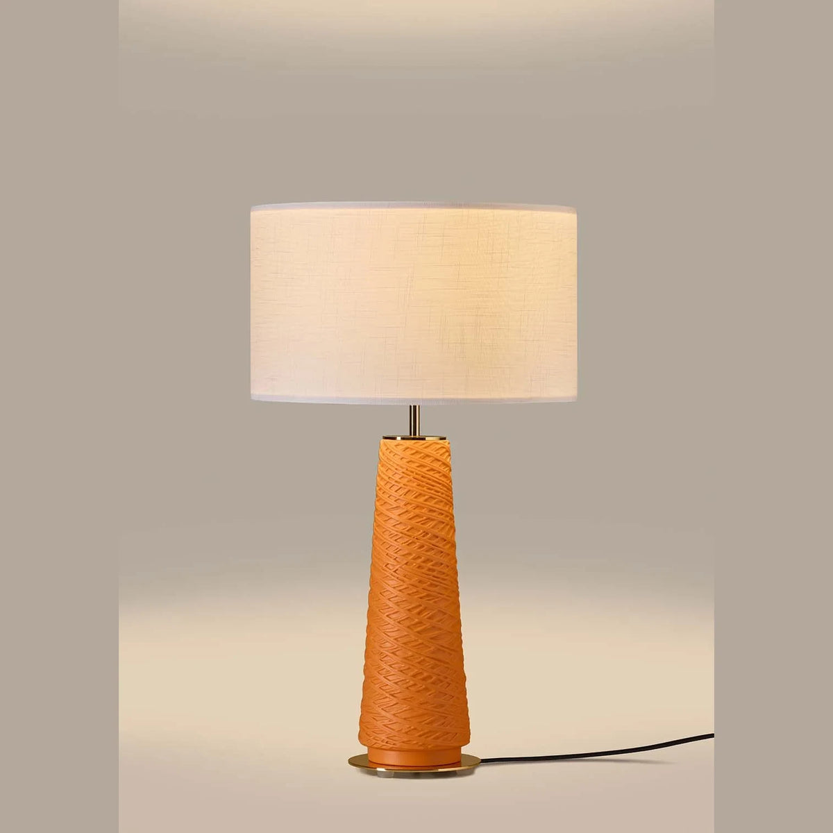 Tapered ceramic column table lamp, lit, with a linen shade (not included)